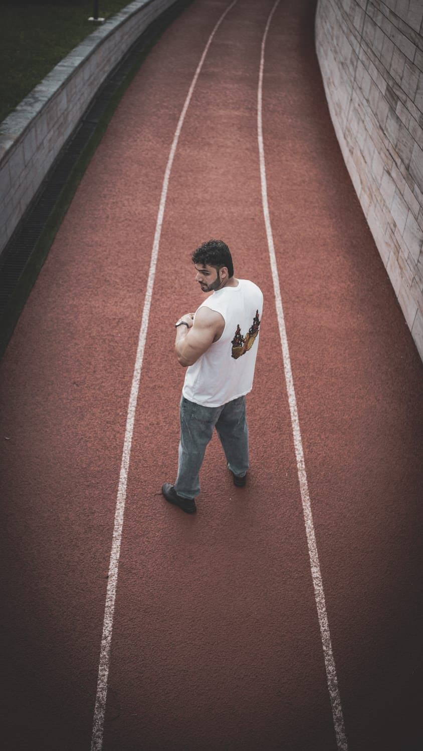 Asfand Khan seen from above, walking along a red running track