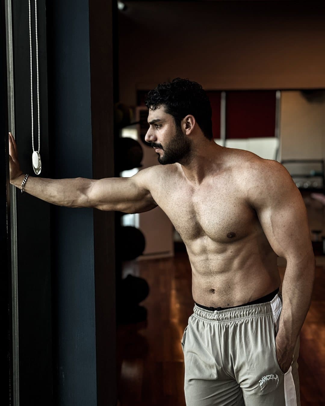 Asfand Khan leaning on a window frame in a dim training studio